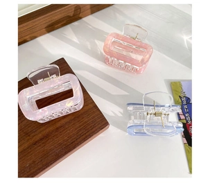 Detail of three rectangular marble acetate hair claws in lavender, orange, and blue colors