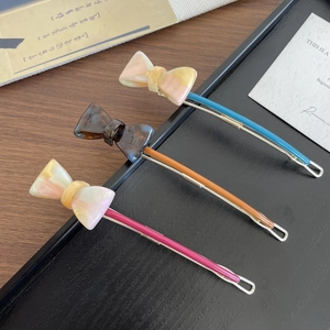 Three elegant agate-patterned resin bow hair clips in blue, brown, and pink on a tray