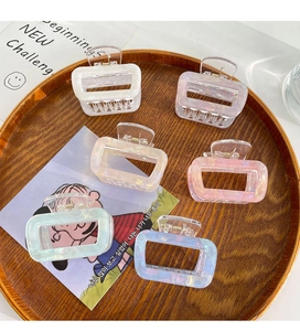 Detailed view of six colorful acetate square hair claws neatly arranged in a wooden tray