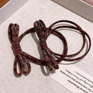 Close-up of two brown leopard print bow hair ties on a textured cream jewelry tray