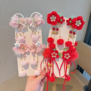Détail de pinces à cheveux chinoises rouges avec de longs rubans et des pompons dorés