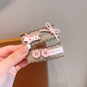 Detail of fabric hair clips with pink bows and buttons for girls on a grey tweed base