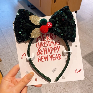 Detail eines Weihnachts-Haarreifens mit grüner Pailletten-Schleife und festlichen Pompons