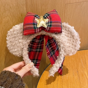 Détail d'un serre-tête oreilles en peluche marron avec nœud écossais et étoile