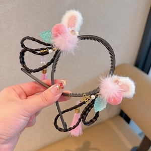 Détail de pompons rouges et breloques de fleurs dorées sur un serre-tête chinois