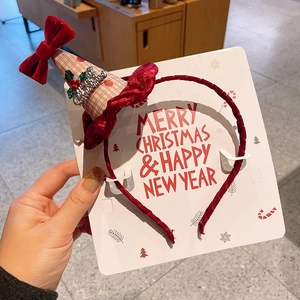 Détail d'un serre-tête de Noël en velours rouge avec chapeau à carreaux et carte festive