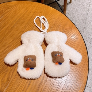 Dettaglio di muffole in pile teddy bianco con toppa a fumetto di toast su tavolo di legno