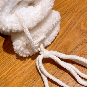 Dettaglio di caldi guanti in lana d'agnello bianco avorio con cordoncino in cotone intrecciato