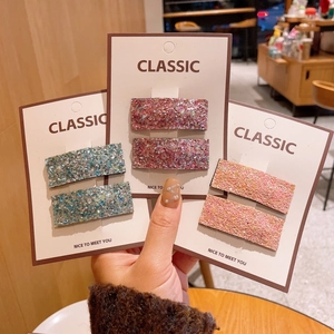 Detail view of rectangular glitter hair clips in blue, purple, and champagne pink tones