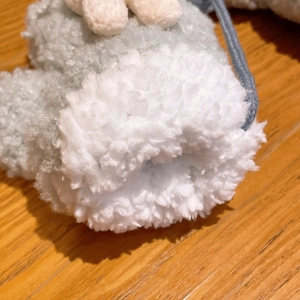 Makro-Detail aus weichem Fleece-Stoff in Blaugrün mit weißem Plüschrand und Kordel