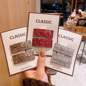 Detail view of sparkling square sequin hair clips in deep red, bronze, and silver on card