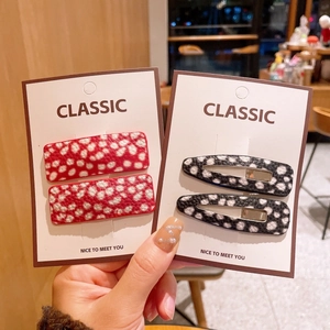 Detail showing red and black polka dot leather hair clips with fine lychee texture