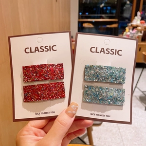 Close-up of sparkling sequin square hair clips in red and blue on a paper card