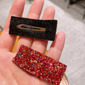 Macro detail of red glitter hair clip with black felt backing and silver metal BB clip