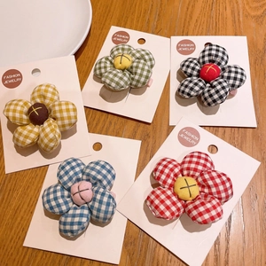 Five-petal fabric plaid flower hair clips in various colors on wooden background