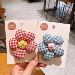 Close-up of padded fabric flower hair clips with red and blue checkered patterns