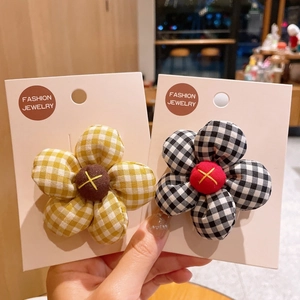 Detail of cute padded fabric sunflower hair clips in yellow and black checkered patterns