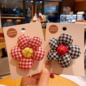 Close-up of padded plaid fabric flower hair clips in red and black gingham patterns