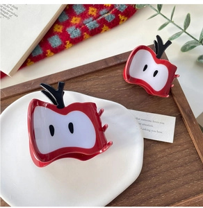 Vue détaillée de pinces à cheveux en forme de pomme rouge en deux tailles sur une assiette