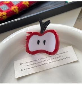 Détail d'une pince à cheveux en forme de pomme rouge sur un plateau décoratif