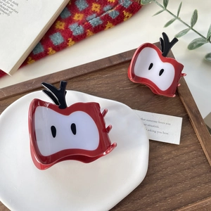 Pinces à cheveux en forme de pomme rouge avec pois noirs sur un plateau en céramique