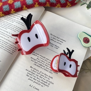 Pinces à cheveux mignonnes en forme de pomme rouge sur un fond de livre ancien