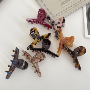 Flat lay of multiple acetate hair claws in various patterns like marble and tortoiseshell