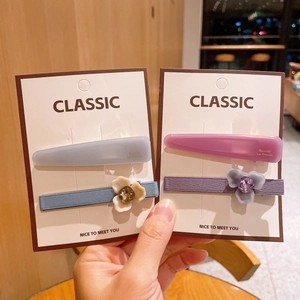 Détail d'un lot de deux barrettes à fleurs en acétate bleu et violet sur carte cadeau