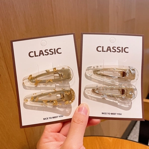 Acrylic water drop hair clips with gold and silver foil accents on classic display card