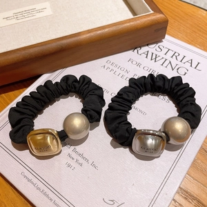 Black fabric scrunchie with classic gold and silver square metal beads on vintage book