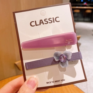 Détail de barrettes violettes avec une fleur mate et une inscription gravée élégante