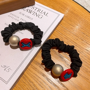 Detail of black fabric scrunchies with champagne pearl and cute red dog ornament