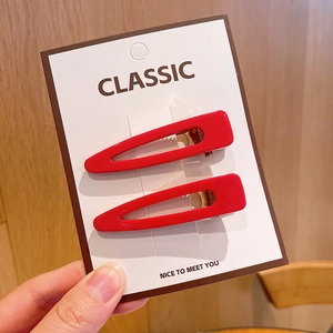 Macro detail of red cutout triangular hair clips on a white classic display card