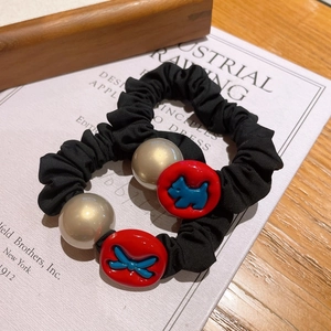 Elegant black scrunchies set with golden pearls and blue dog charms on books
