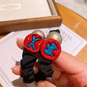 Detail of black scrunchies with red puppy charms and champagne gold pearls decor