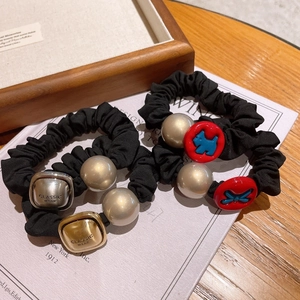Detail view of black scrunchies with gold metal cubes and blue dog charms on wooden tray