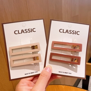 Detail of minimalist rectangular acrylic hair clips in beige and pink on white card