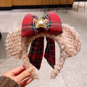 Détail du serre-tête en peluche avec nœud à carreaux rouges et ornement d'étoile dorée