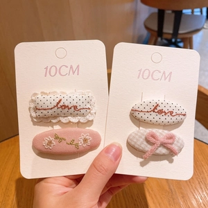 Détail de barrettes en tissu de 10CM avec broderie florale et nœud à carreaux rose