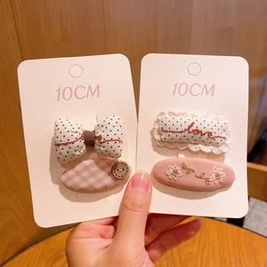 Détail de quatre barrettes en tissu à carreaux roses et brodées sur des cartons