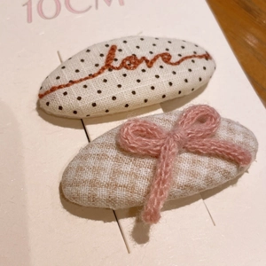 Gros plan de barrettes à carreaux roses avec broderie et nœud sur carte de support