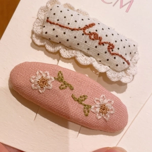 Gros plan de barrettes en tissu brodé fait main avec dentelle et motifs de marguerites