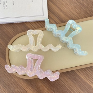 Detail of pearlescent oversized wave hair claws with heart cutout and gold spring mechanism
