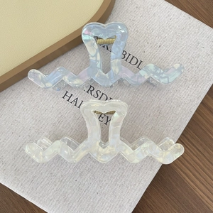 Detail of colorful wave claw clips with heart cutout in iridescent blue and cream