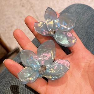 Détail de deux pinces à cheveux fleurs bleues irisées avec pierres en zircon