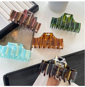 Close-up of five acetate hair claws with striped patterns and heart-shaped cutouts