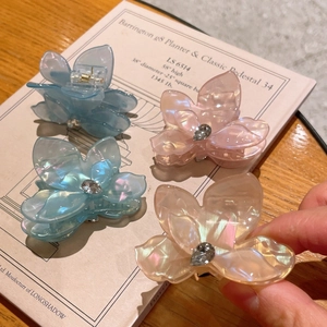 Gros plan de pinces à cheveux fleurs irisées avec strass gouttes sur un livre
