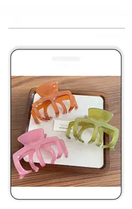 Dettaglio di tre mollette per capelli in resina traslucida nei colori arancione, verde e rosa