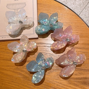 Détails de six pinces à cheveux fleurie nacrées avec strass sur une table en bois