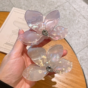 Vue rapprochée de pinces à cheveux fleur avec strass en coloris violet et blanc perle